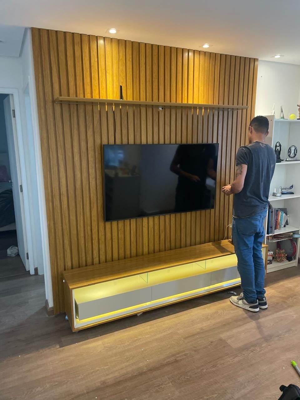 Profissional ajustando painel ripado com televisão em sala