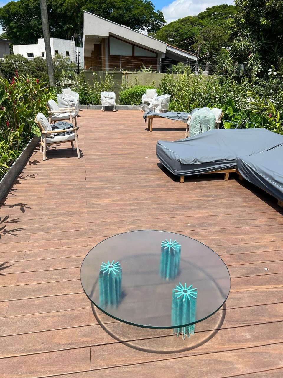 Deck externo com mobiliário protegido e mesa de vidro